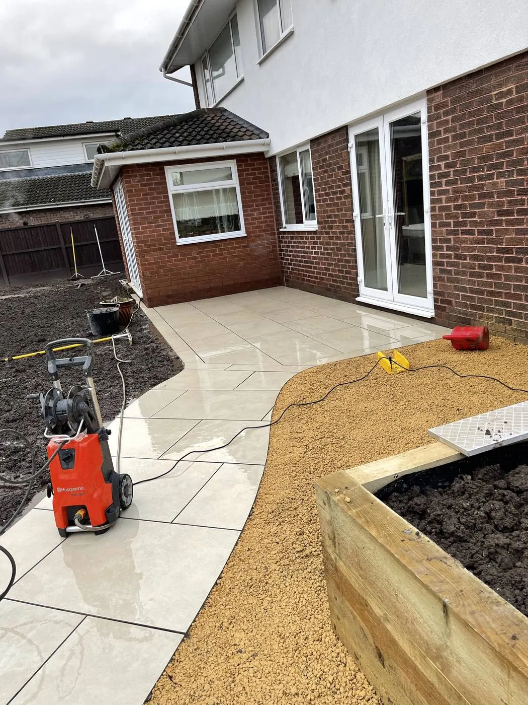 Timber sleeper raised beds filled with soil beside a newly laid stone path
